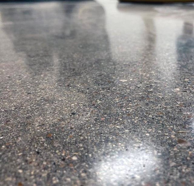 A medium aggregate exposed polished concrete floor at a church in North Dallas. This pour had no special preparation for polishing and no color was added during the polishing process. The natural variation in the concrete aggregate gives this tan/gray floor a terrazzo like finish.