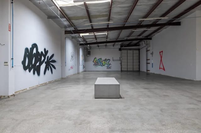 This image represents a low-gloss polished concrete floor Low-gloss polished concrete floor in a graffiti-covered warehouse, illustrating a Level 1 or 2 finish with minimal reflectivity